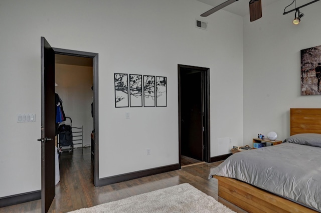 bedroom with a ceiling fan, baseboards, visible vents, and wood finished floors