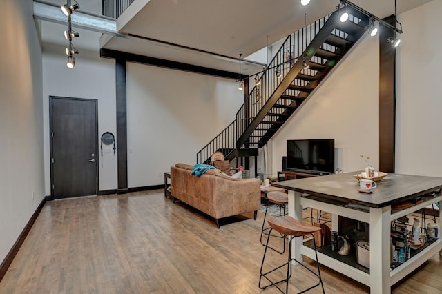 living room with a high ceiling, stairway, baseboards, and wood finished floors