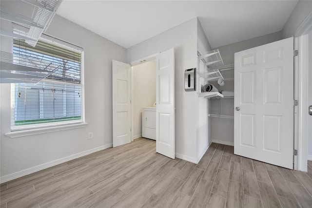 unfurnished bedroom with washer / dryer, light wood-style flooring, baseboards, and a closet