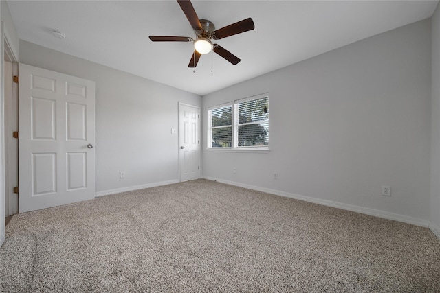 carpeted spare room featuring ceiling fan and baseboards