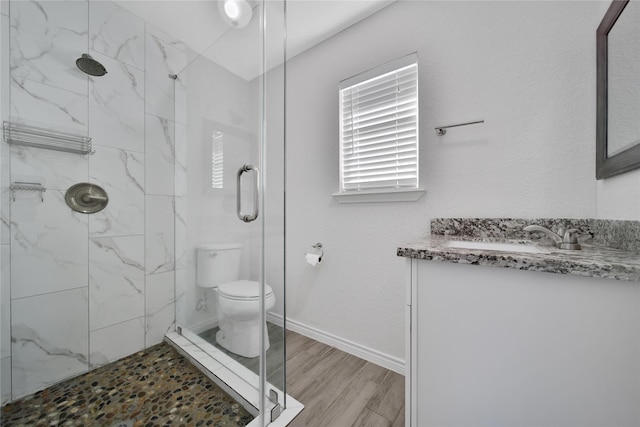 full bath with toilet, wood finished floors, vanity, baseboards, and a shower stall