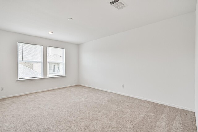 unfurnished room with visible vents, light carpet, and baseboards