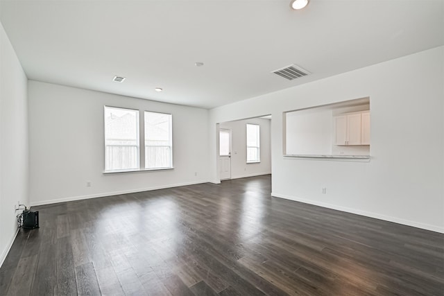 spare room with dark wood-style floors, visible vents, and baseboards