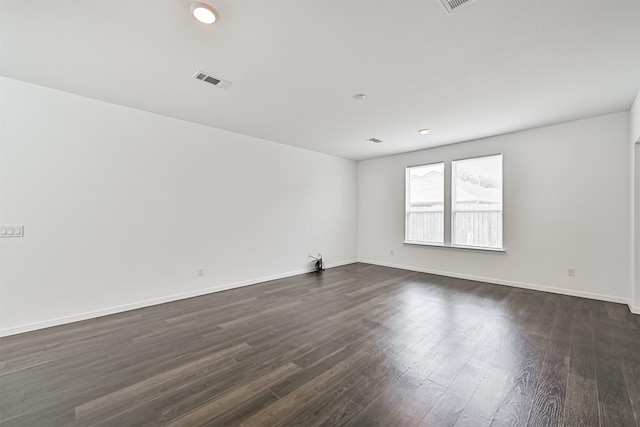 spare room featuring dark wood-style floors, visible vents, and baseboards