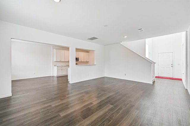 unfurnished living room with dark wood-style floors, visible vents, stairway, and baseboards