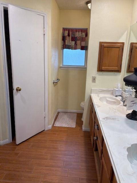 9427 Walnut Glen Dr, Houston, TX 77064 - bathroom featuring baseboards, double vanity, toilet, a sink, and wood finished floors