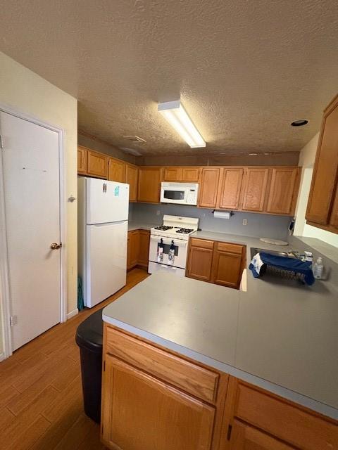 9427 Walnut Glen Dr, Houston, TX 77064 - kitchen with a peninsula, white appliances, wood finished floors, and a textured ceiling