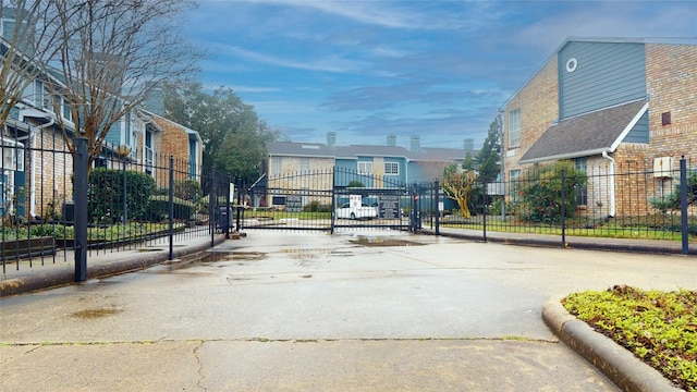 view of street featuring a gate, a residential view, a gated entry, and curbs