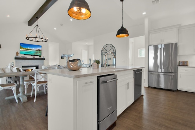 kitchen with a lit fireplace, high end fridge, dark wood-type flooring, and a sink