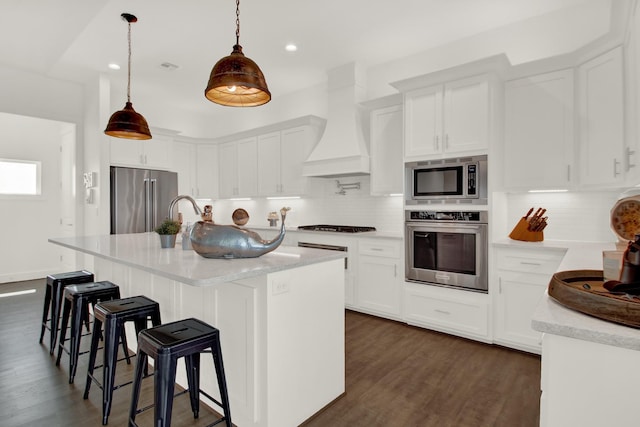 kitchen with light countertops, appliances with stainless steel finishes, custom exhaust hood, decorative backsplash, and dark wood finished floors