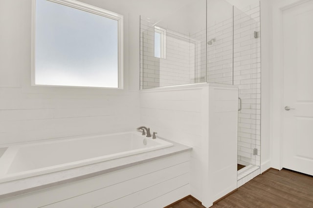 bathroom featuring a bath, a stall shower, and wood finished floors