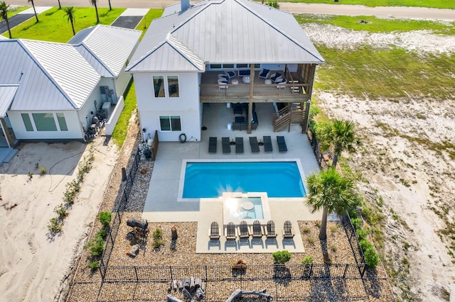 back of house featuring a pool with connected hot tub, a fenced backyard, a patio, and a balcony