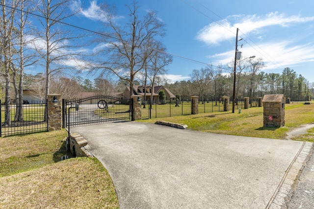 view of street featuring street lighting, a gate, and aphalt driveway