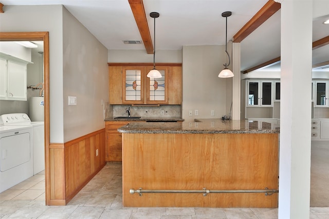 kitchen with a wainscoted wall, visible vents, a sink, separate washer and dryer, and dark stone counters