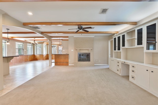 unfurnished living room with a fireplace, light colored carpet, beamed ceiling, and built in study area