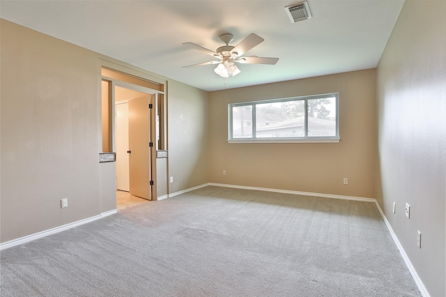 spare room featuring baseboards, visible vents, a ceiling fan, and light colored carpet