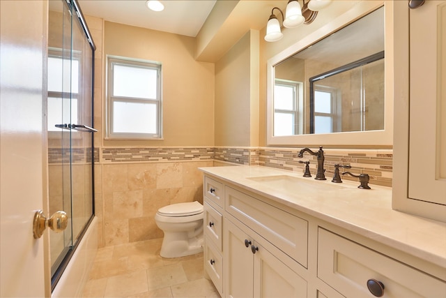 full bathroom with tile patterned flooring, toilet, shower / bath combination with glass door, vanity, and tile walls