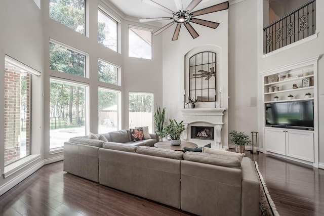 living room featuring baseboards, a fireplace, a high ceiling, and dark wood-style flooring