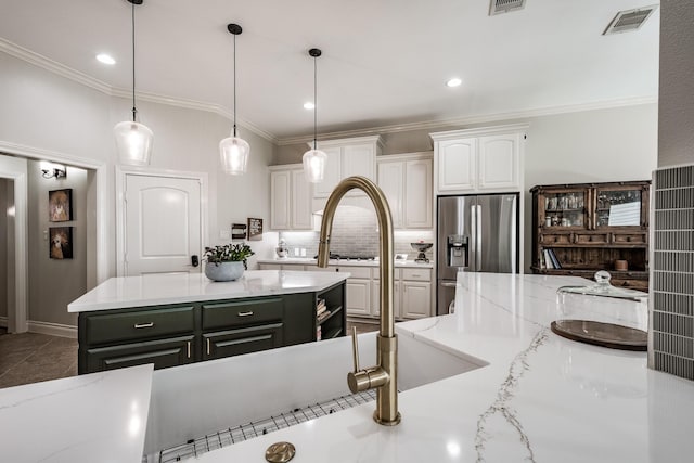 kitchen featuring ornamental molding, stainless steel refrigerator with ice dispenser, visible vents, and white cabinets