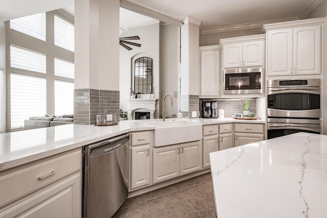 kitchen featuring ceiling fan, stainless steel appliances, a sink, white cabinets, and crown molding