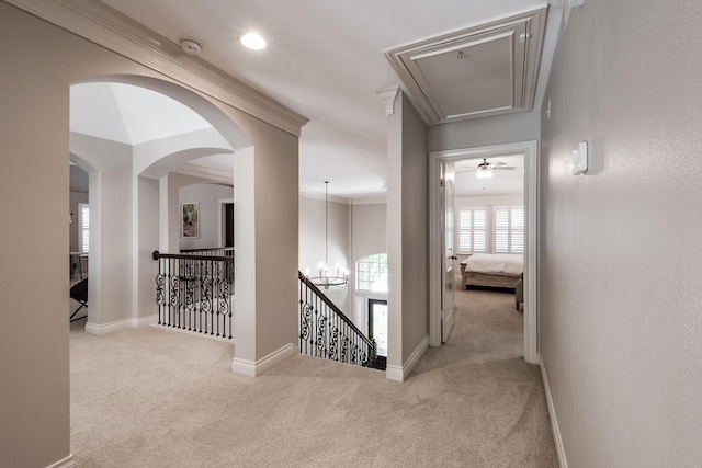 corridor with carpet, an inviting chandelier, attic access, an upstairs landing, and baseboards