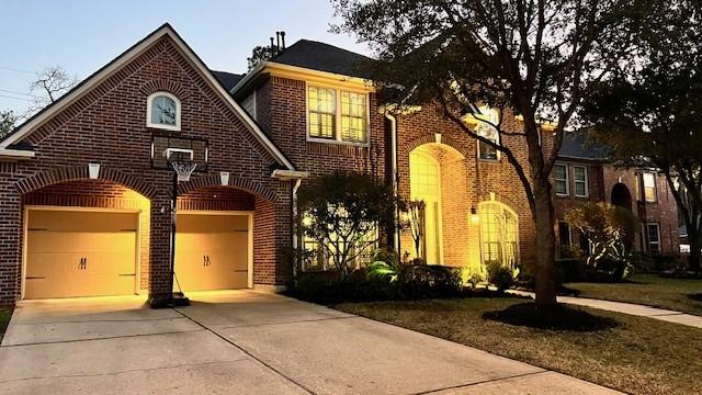 view of front facade with a garage, brick siding, and driveway