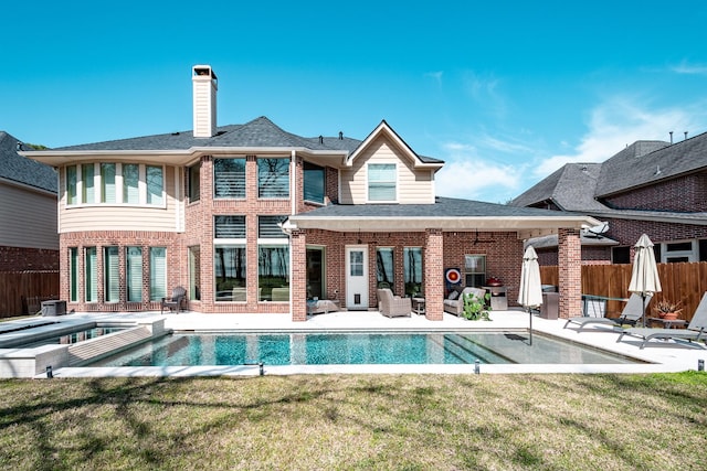 back of property with a yard, a patio area, brick siding, and fence