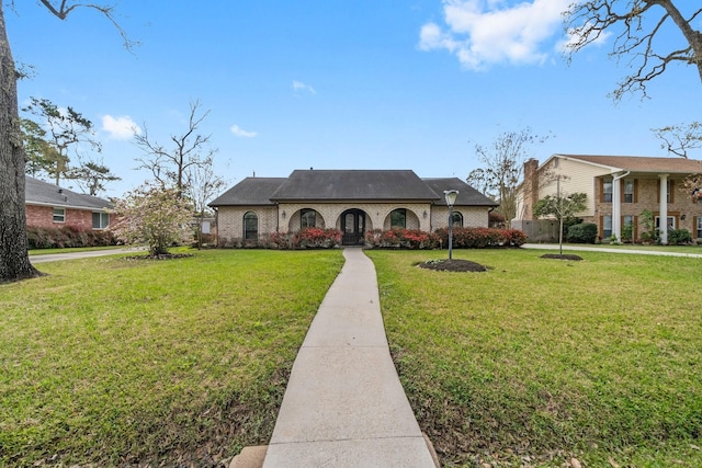 french country home featuring brick siding and a front yard