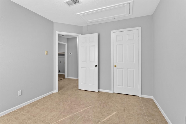 unfurnished bedroom featuring visible vents, tile patterned flooring, attic access, and baseboards