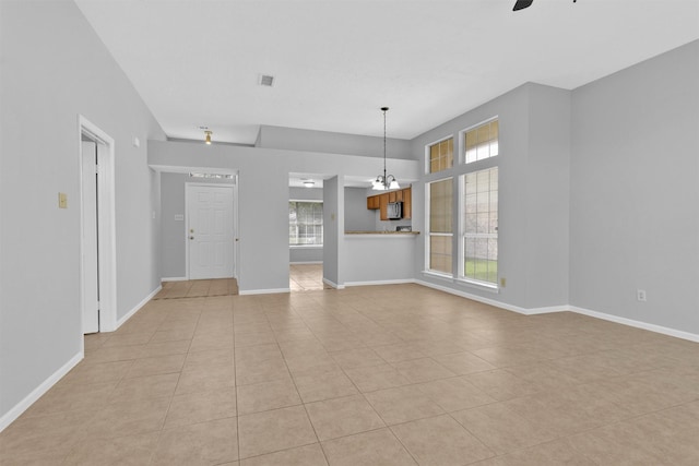 unfurnished room featuring light tile patterned flooring, baseboards, visible vents, and ceiling fan with notable chandelier