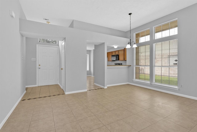 interior space featuring light tile patterned flooring, a notable chandelier, and baseboards