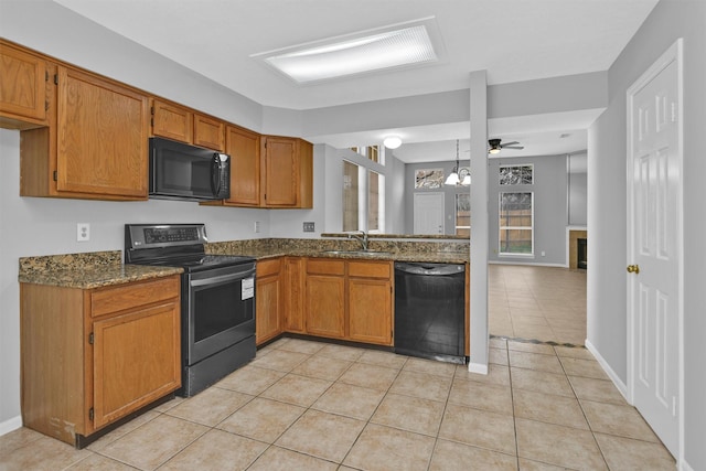 kitchen with light tile patterned floors, black appliances, brown cabinetry, and a sink