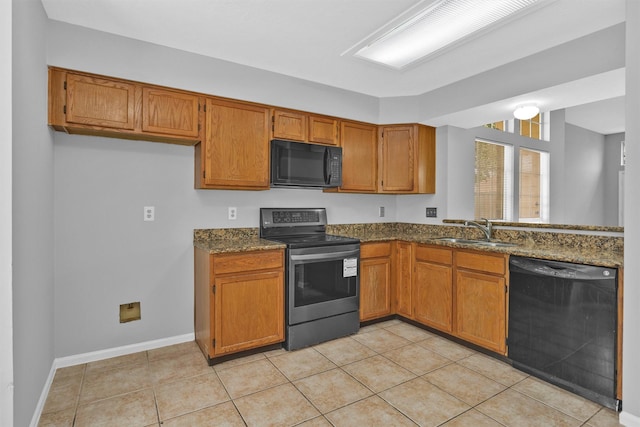 kitchen with dark stone counters, brown cabinets, black appliances, a sink, and light tile patterned flooring