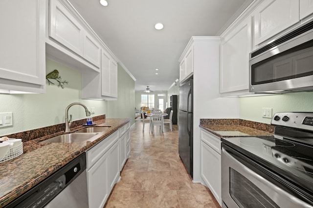 kitchen with white cabinetry, appliances with stainless steel finishes, dark stone counters, and a sink