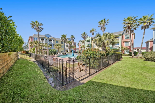 view of property's community featuring a residential view, a yard, a swimming pool, and fence