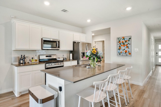 kitchen featuring visible vents, backsplash, appliances with stainless steel finishes, light wood-style floors, and white cabinetry