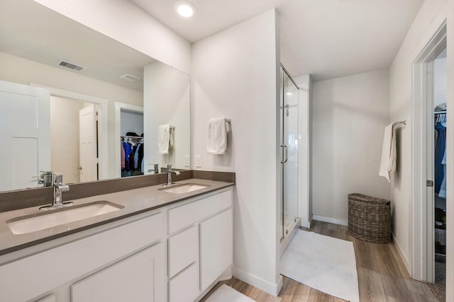 full bath featuring a stall shower, visible vents, a sink, and wood finished floors