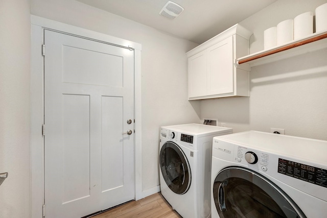 laundry room with visible vents, light wood finished floors, washer and clothes dryer, and cabinet space