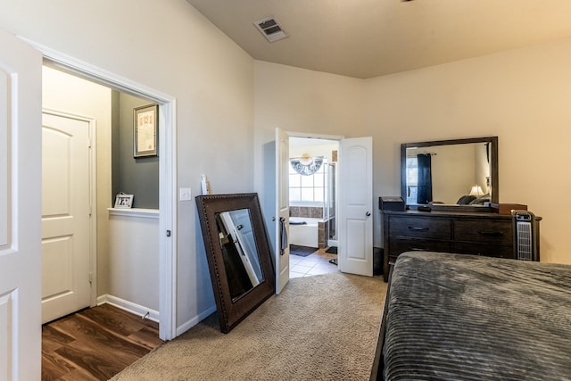 bedroom with light colored carpet, visible vents, ensuite bath, and baseboards