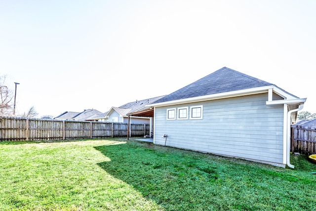 rear view of house with a fenced backyard and a lawn