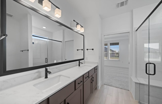 full bathroom with a stall shower, visible vents, a sink, and double vanity