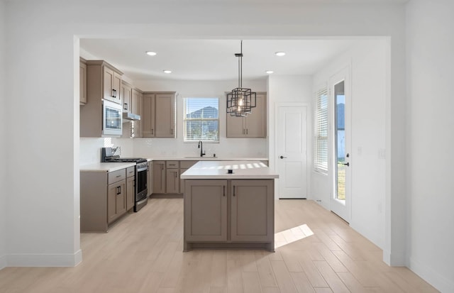 kitchen with gray cabinets, light countertops, a sink, stainless steel gas range, and built in microwave