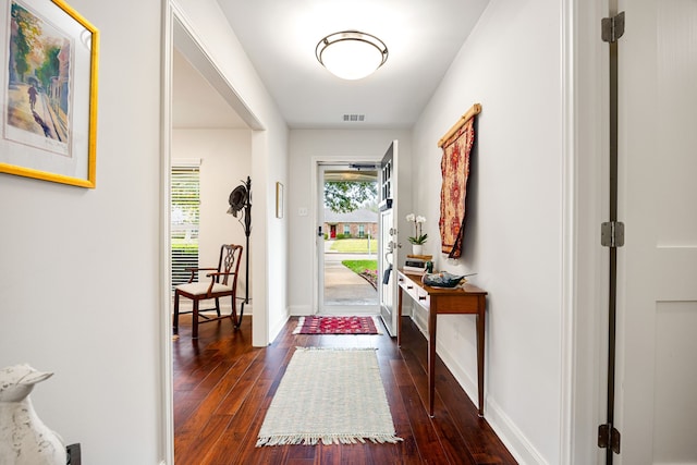 doorway featuring baseboards, visible vents, and dark wood finished floors