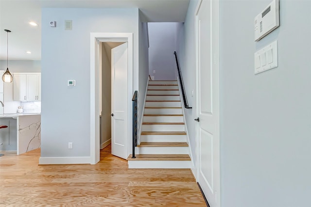 staircase featuring recessed lighting, visible vents, baseboards, and wood finished floors