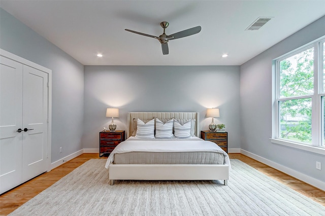 bedroom featuring a ceiling fan, visible vents, baseboards, and wood finished floors