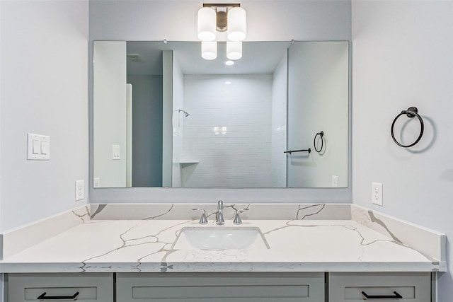 full bathroom with visible vents, a tile shower, and vanity