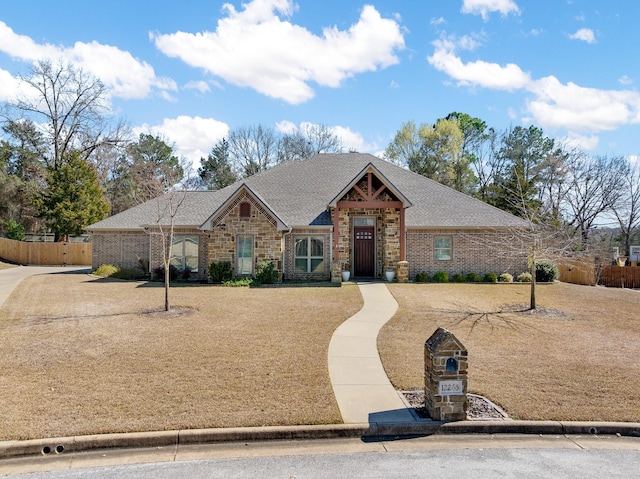 view of front of house with stone siding, fence, and roof with shingles