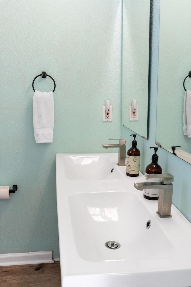 bathroom with a sink, baseboards, and wood finished floors