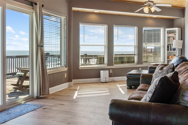 living area featuring ceiling fan, plenty of natural light, baseboards, and wood finished floors