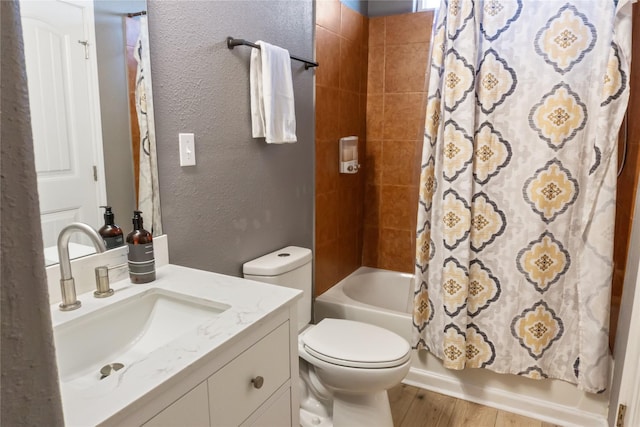 bathroom with a textured wall, toilet, wood finished floors, vanity, and shower / bathtub combination with curtain
